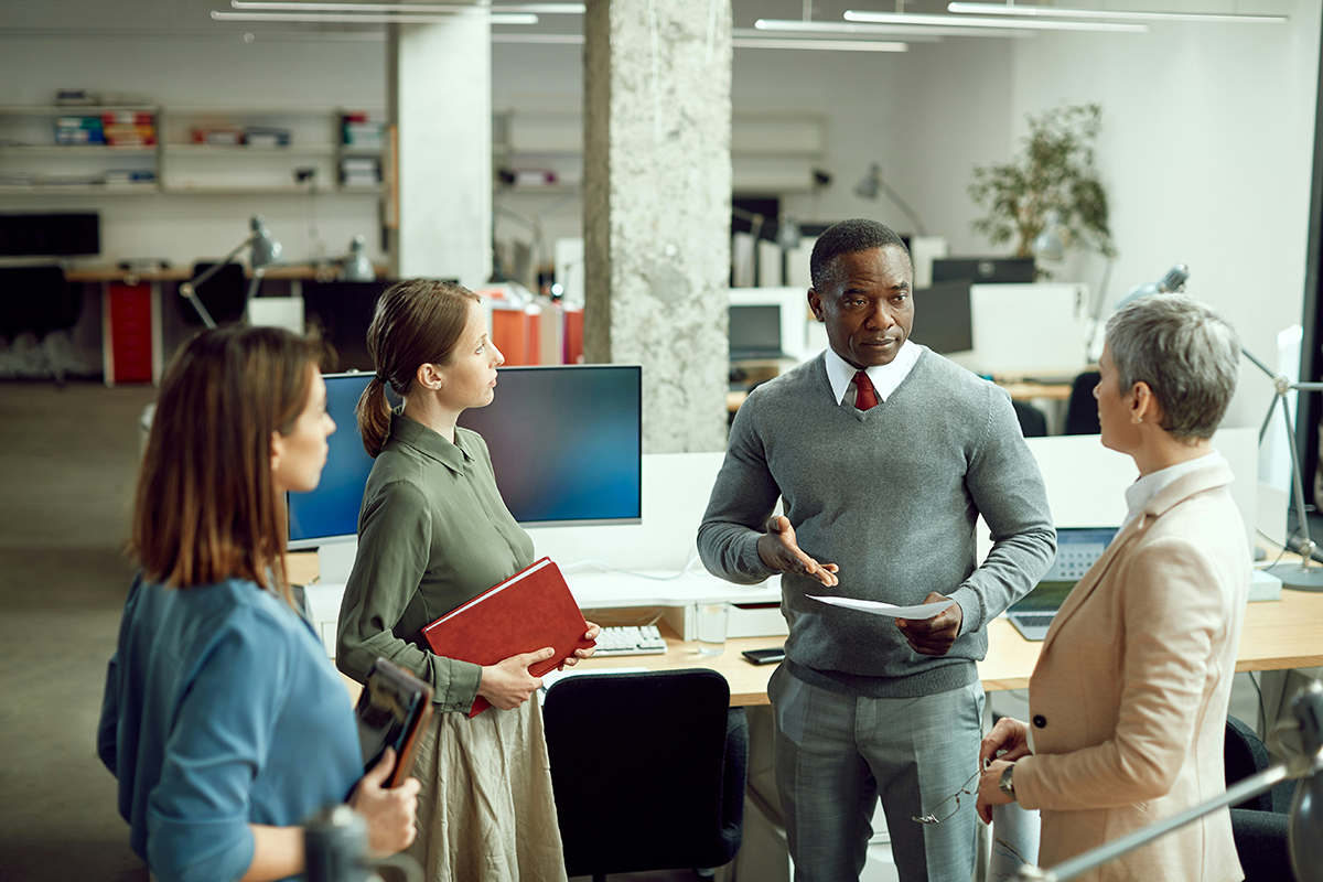 A group of colleagues in discussion in an open-plan office